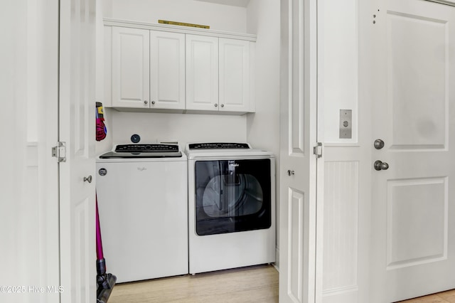 clothes washing area with washer and dryer and cabinet space