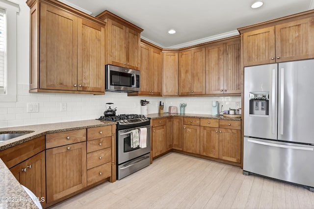 kitchen with light stone countertops, stainless steel appliances, and brown cabinets