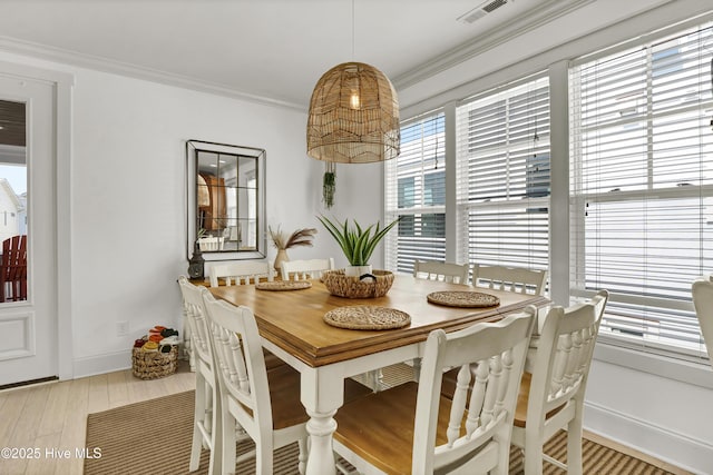 dining room featuring visible vents, baseboards, crown molding, and wood finished floors