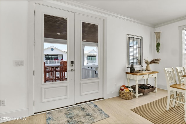 doorway to outside featuring baseboards, ornamental molding, wood finished floors, and a wealth of natural light