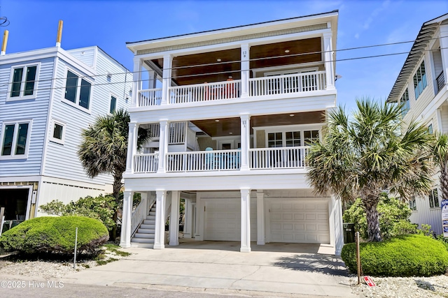 beach home with stairway, driveway, a balcony, and a garage
