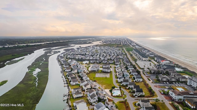 aerial view at dusk with a water view and a residential view