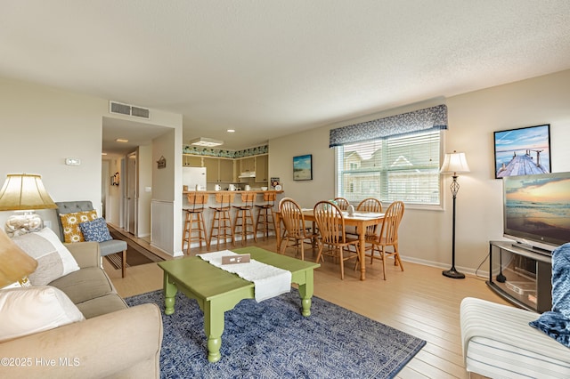 living room with visible vents, wood finished floors, and baseboards