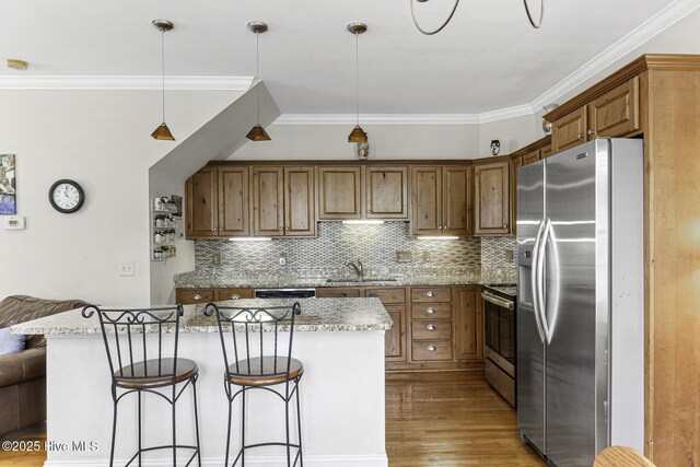 kitchen featuring brown cabinetry, stainless steel appliances, light stone countertops, and ornamental molding