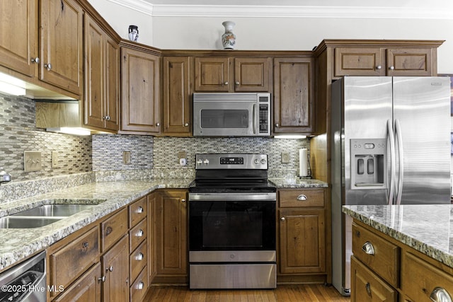 kitchen with ornamental molding, a sink, appliances with stainless steel finishes, and wood finished floors