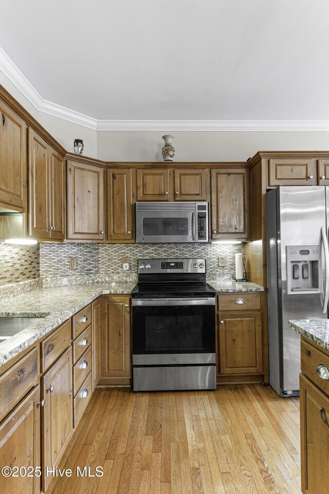 kitchen with ornamental molding, a sink, appliances with stainless steel finishes, and wood finished floors
