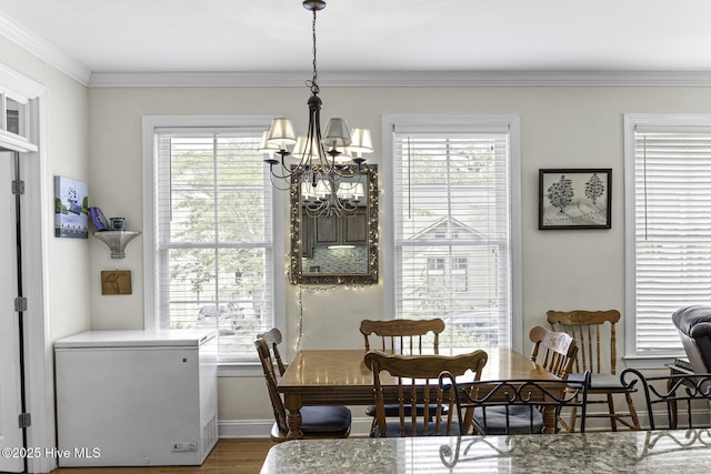 dining area featuring an inviting chandelier, wood finished floors, a healthy amount of sunlight, and crown molding