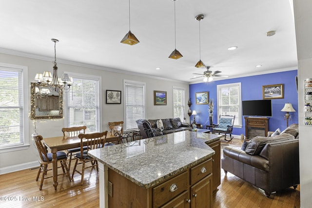 kitchen with baseboards, light wood-type flooring, open floor plan, and crown molding
