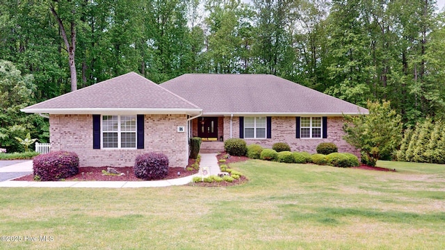 ranch-style home with a front lawn, brick siding, and roof with shingles
