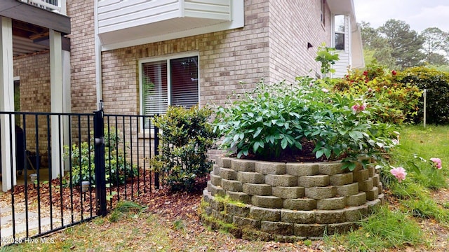 doorway to property featuring brick siding and fence