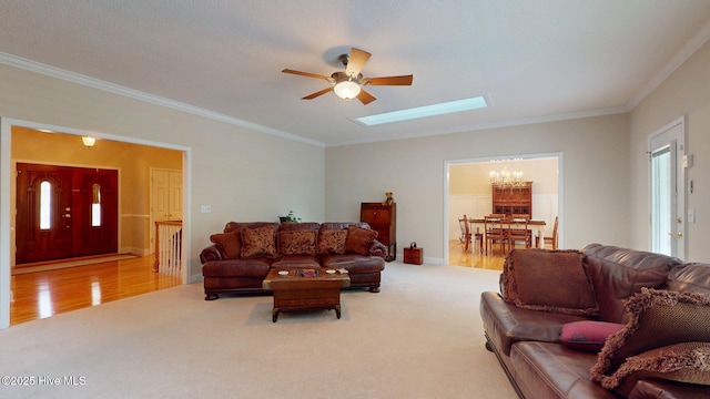 carpeted living area with a skylight, wood finished floors, crown molding, and ceiling fan with notable chandelier