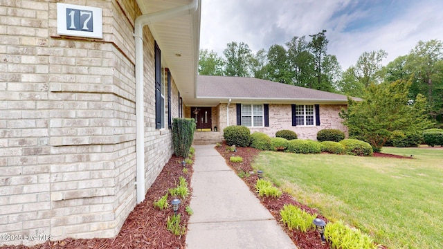 view of exterior entry featuring a yard and brick siding