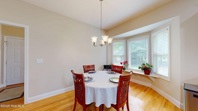dining room with a notable chandelier, baseboards, and light wood-style floors