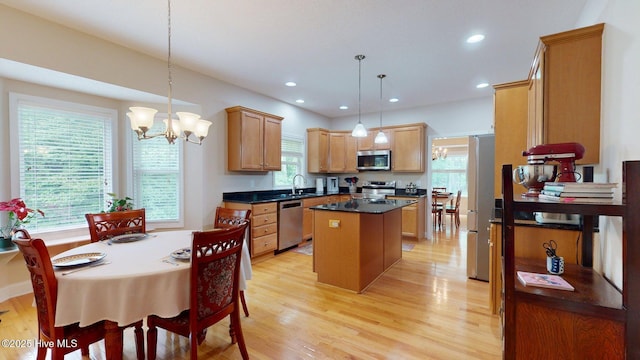 kitchen with a sink, a chandelier, a kitchen island, dark countertops, and appliances with stainless steel finishes