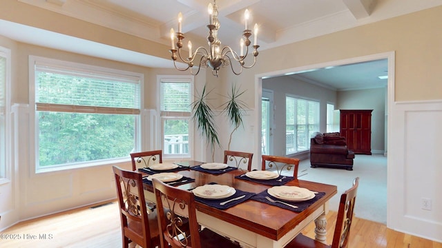 dining room featuring crown molding, visible vents, light wood-style floors, a decorative wall, and a notable chandelier