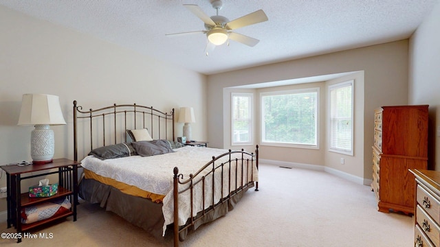 bedroom with a ceiling fan, a textured ceiling, light colored carpet, and baseboards