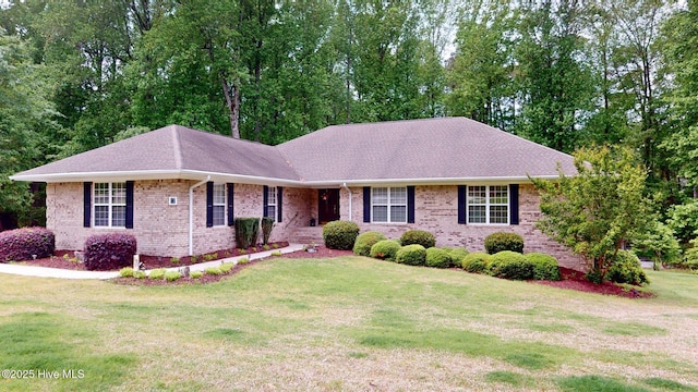single story home with a front yard, a shingled roof, and brick siding