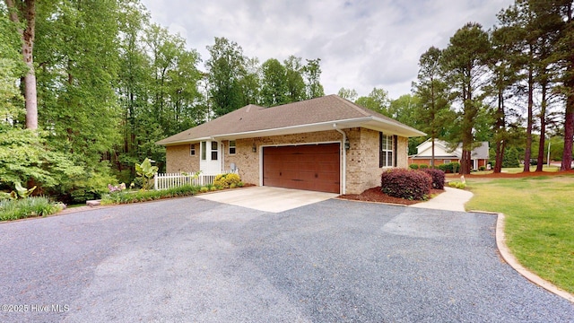 ranch-style house with fence, brick siding, aphalt driveway, and an attached garage
