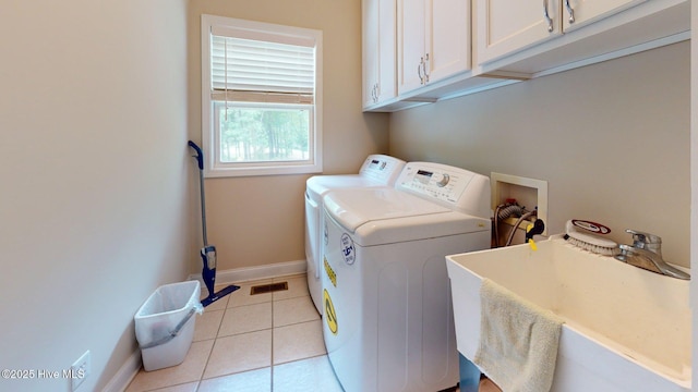 laundry area featuring a sink, baseboards, light tile patterned flooring, washer and dryer, and cabinet space