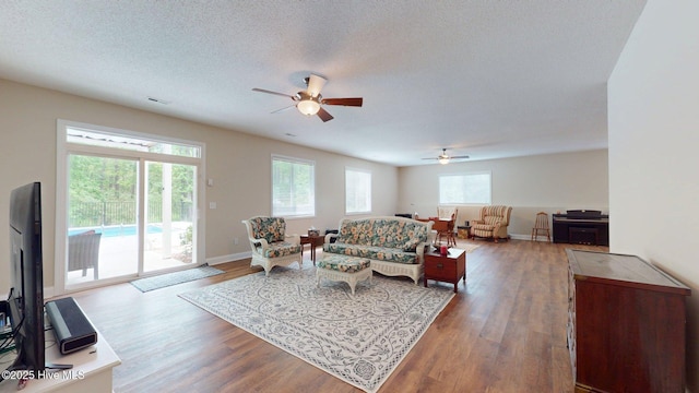 living area with visible vents, wood finished floors, ceiling fan, and a textured ceiling