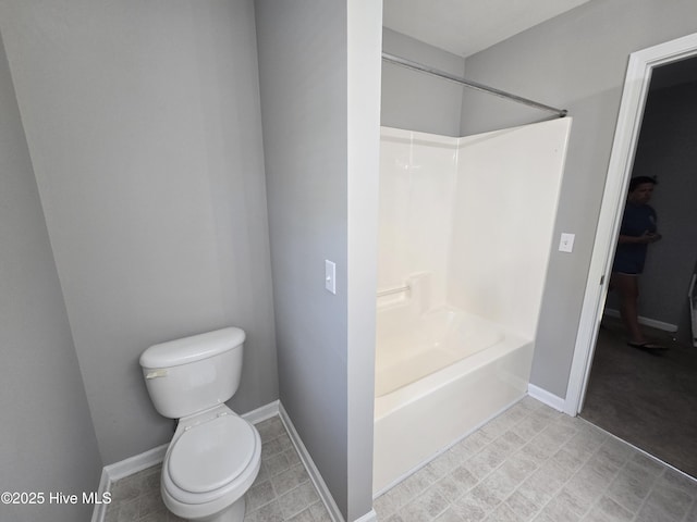 bathroom featuring toilet, shower / bathtub combination, and baseboards