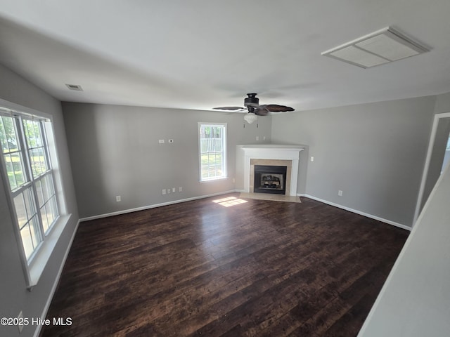 unfurnished living room with healthy amount of natural light, dark wood-style floors, ceiling fan, and baseboards
