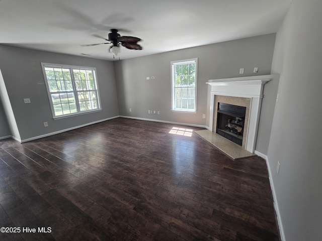 unfurnished living room with dark wood finished floors, ceiling fan, a high end fireplace, and baseboards