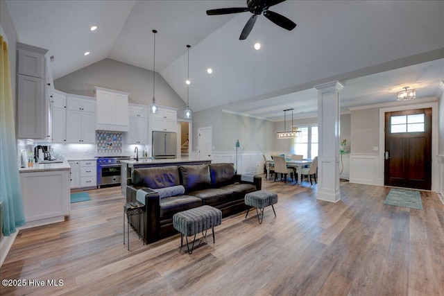 living room with high vaulted ceiling, a wainscoted wall, and a decorative wall