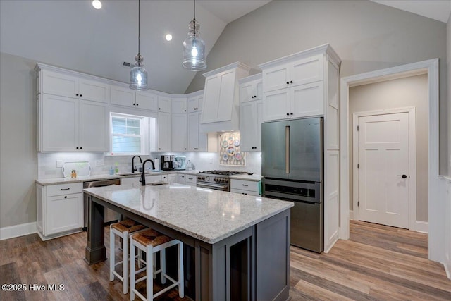 kitchen with appliances with stainless steel finishes, lofted ceiling, and white cabinets