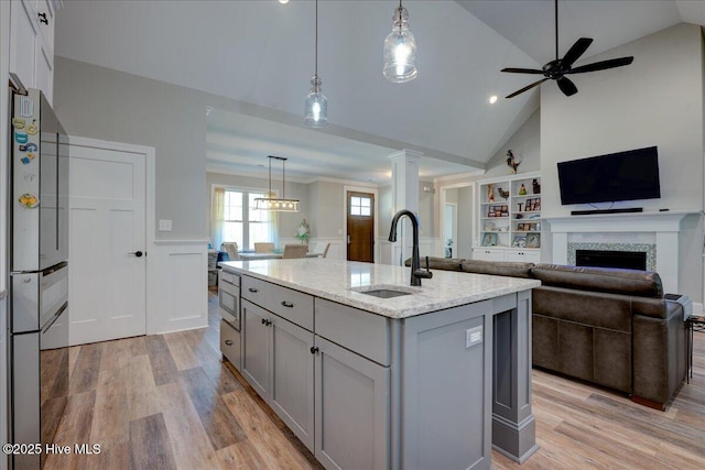 kitchen featuring open floor plan, gray cabinetry, a sink, and light wood-style floors
