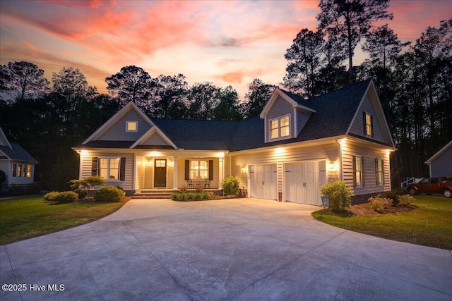 craftsman house featuring a lawn, covered porch, a shingled roof, and driveway