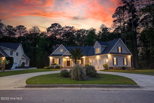 view of front of home featuring a lawn, curved driveway, and a garage