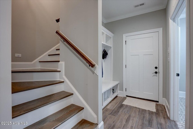mudroom featuring baseboards, ornamental molding, wood finished floors, and visible vents