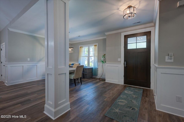 entryway with a wainscoted wall, ornamental molding, and a decorative wall