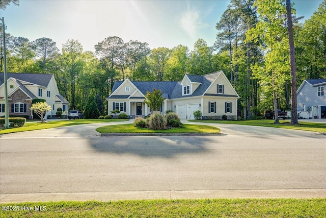 new england style home featuring an attached garage, a front lawn, and concrete driveway