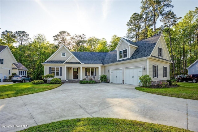 view of front of home featuring a porch, roof with shingles, driveway, and a front yard