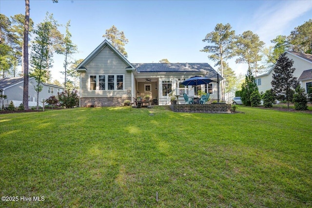back of property featuring a lawn and ceiling fan