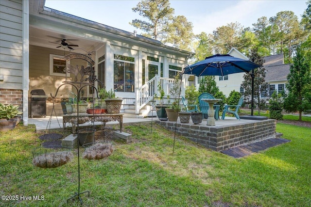 rear view of house with a sunroom, a ceiling fan, a patio area, and a yard