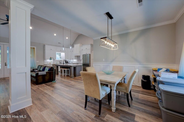 dining room featuring ornamental molding, wood finished floors, and a wainscoted wall