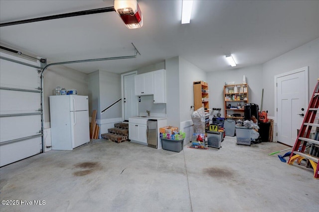 garage featuring a sink, a garage door opener, and freestanding refrigerator