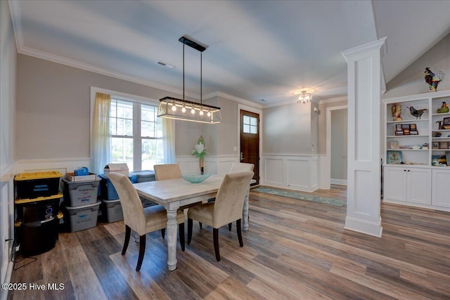 dining space with wainscoting, a decorative wall, decorative columns, wood finished floors, and ornamental molding