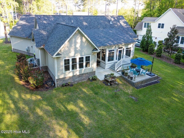 back of property with a yard, a shingled roof, a sunroom, and a patio area