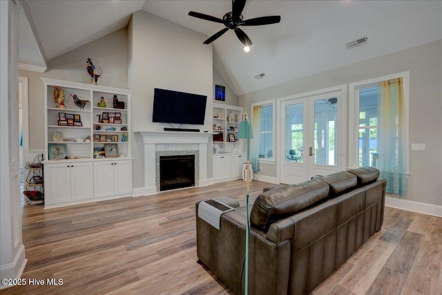 living room featuring a ceiling fan, french doors, visible vents, a fireplace, and high vaulted ceiling