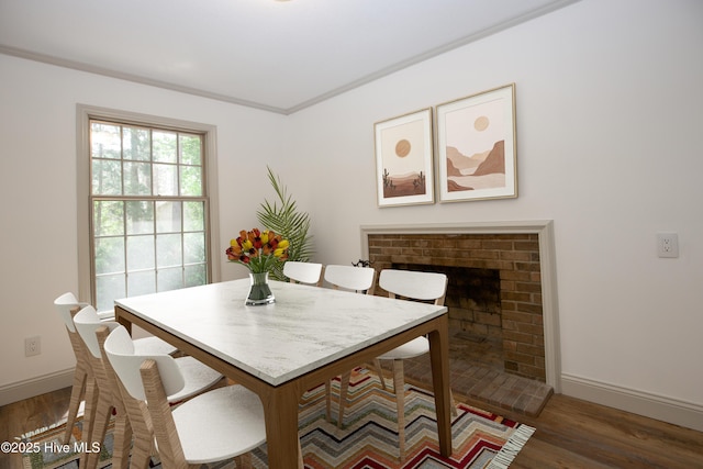 dining space with baseboards, wood finished floors, and a fireplace
