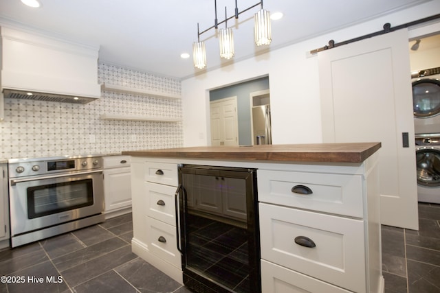 kitchen featuring stacked washer / drying machine, a barn door, beverage cooler, wood counters, and oven