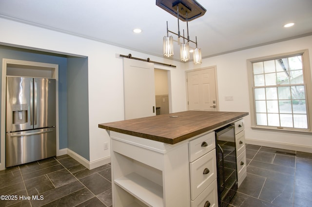 kitchen featuring baseboards, beverage cooler, stainless steel refrigerator with ice dispenser, a barn door, and wood counters