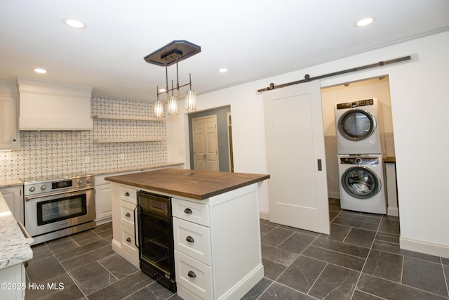 kitchen with stacked washer and clothes dryer, oven, beverage cooler, a barn door, and wood counters