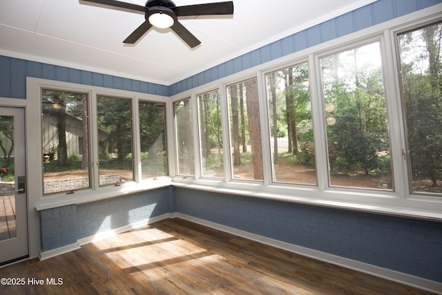 unfurnished sunroom with baseboards, brick wall, and wood finished floors