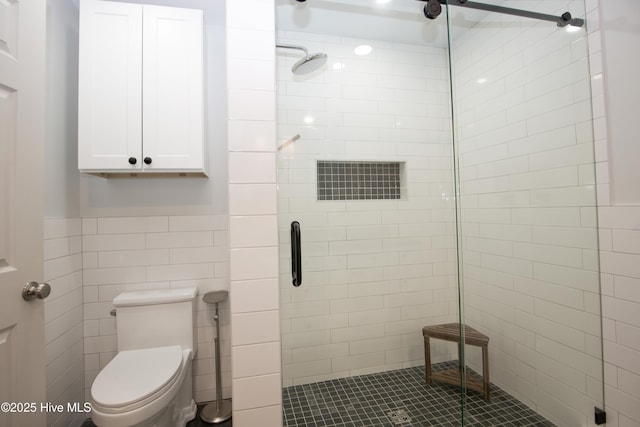 full bathroom featuring toilet, tile walls, wainscoting, and a stall shower