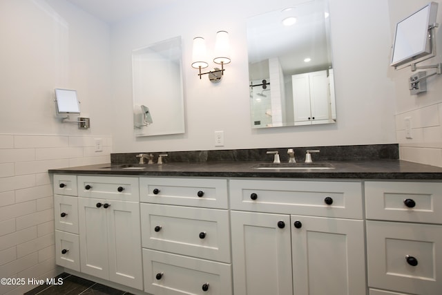 bathroom with double vanity, a sink, a shower, and tile walls